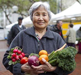Older woman holding vegetables at a farmer's market